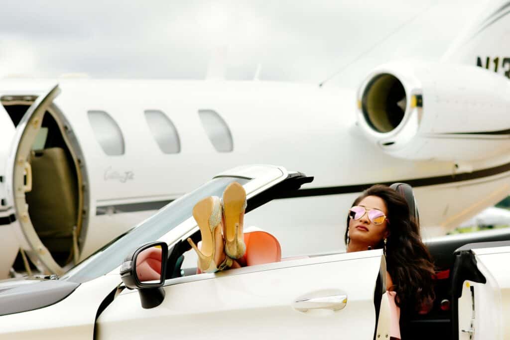 mujer en un coche frente a un jet privado